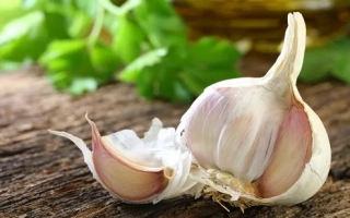 Головки чеснока на деревянной поверхности с зеленью на фоне - Аксакал