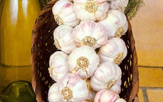 Головки чеснока в корзине на фоне бутылки и зелени - Лосевский