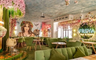 Интерьер кафе с зелёными диванами и надписью FREYA на стене - Фрея