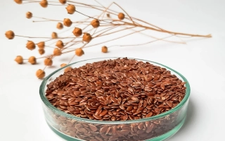 Стеклянная чаша с льняными семенами на белом фоне с веточкой льна - Иванивский