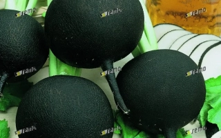 Черные редисы с зелеными листьями и нарезанными кольцами на фоне - КУЛАТА