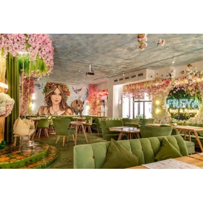 Интерьер кафе с зелёными диванами и надписью FREYA на стене - Фрея