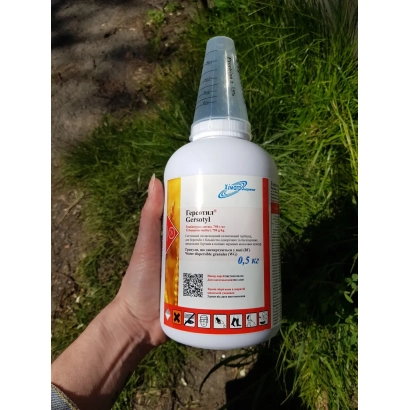 Бутелка гербициду Адор 750 в.г. з етикеткою на фоні трави - Адор 750 в.г., (Трибенурон-метил 750 г/л)