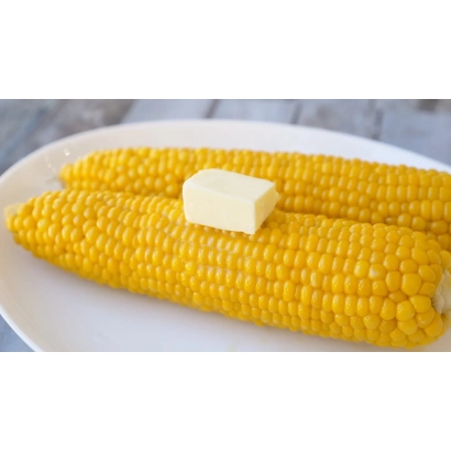 Два варені початки кукурудзи з шматком масла на білій тарілці - ОЛЬГА М