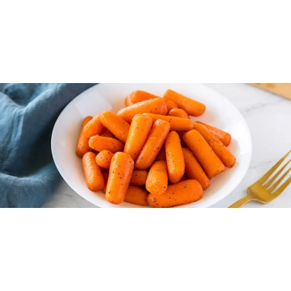 Белая тарелка с нарезанной морковью на фоне синей ткани - БЕЙБИ