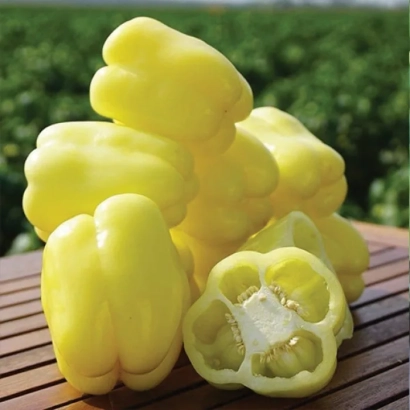 Желтый перец на деревянной поверхности, один плод разрезан пополам - Белладонна F1