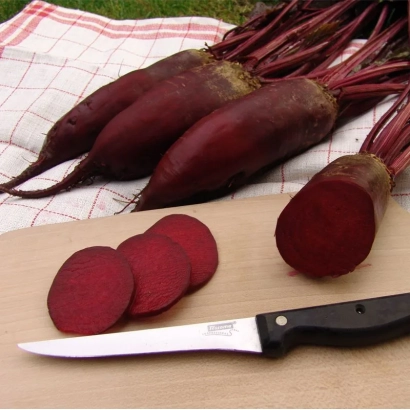 Beetroot roots and sliced pieces on a wooden board with a knife - Monorubra
