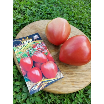 Пакет семян томата СЕРДЦЕ АМУРА на деревянной доске с двумя красными помидорами на фоне травы.